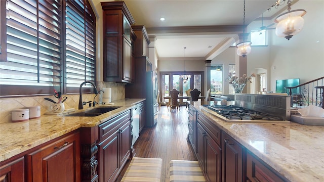 kitchen featuring pendant lighting, sink, ornamental molding, tasteful backsplash, and stainless steel gas cooktop