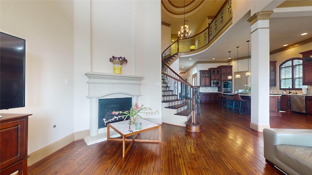 living room featuring a chandelier, a towering ceiling, dark wood-type flooring, and ornamental molding