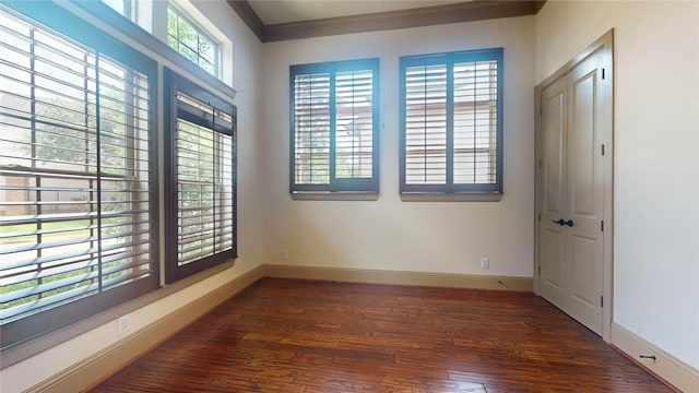 empty room with dark hardwood / wood-style flooring and ornamental molding