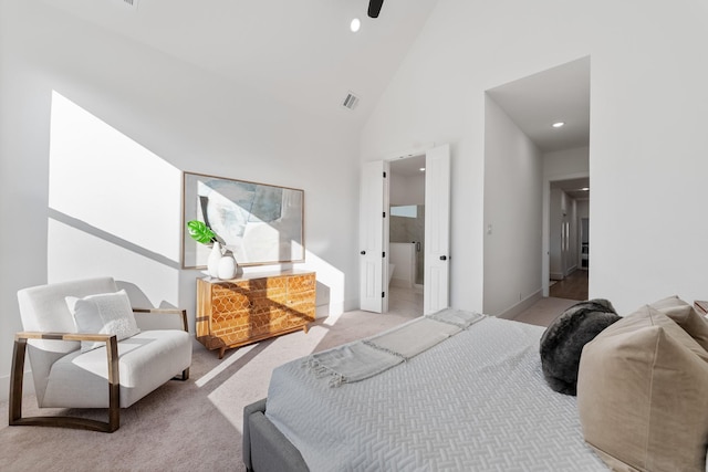 carpeted bedroom featuring high vaulted ceiling and ensuite bath