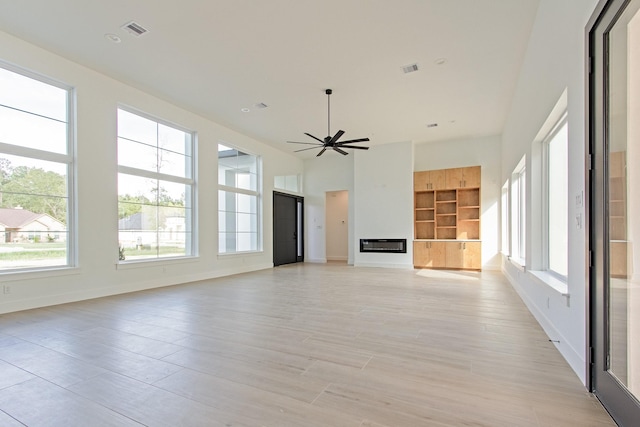 unfurnished living room with ceiling fan, a healthy amount of sunlight, and built in features