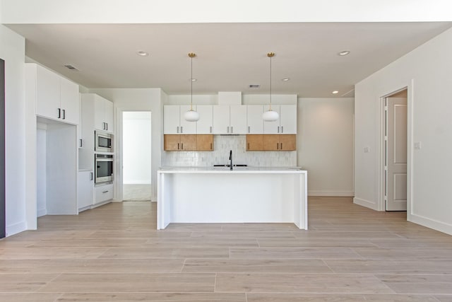 kitchen featuring pendant lighting, white cabinetry, a kitchen island with sink, and appliances with stainless steel finishes