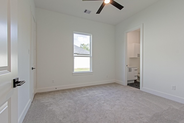 unfurnished bedroom featuring ensuite bathroom, ceiling fan, and light colored carpet