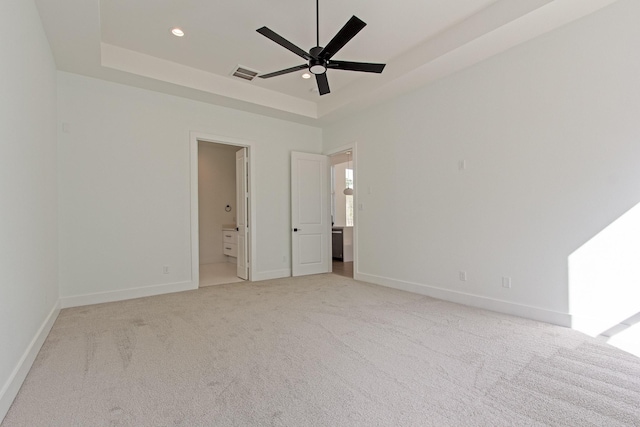 carpeted spare room featuring a tray ceiling and ceiling fan