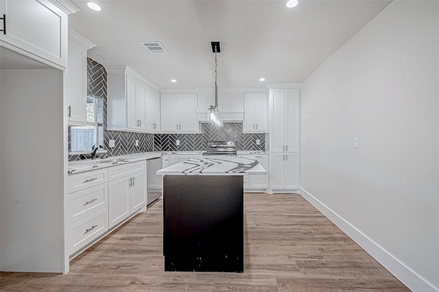 kitchen featuring decorative light fixtures, a kitchen island, white cabinetry, and stainless steel appliances