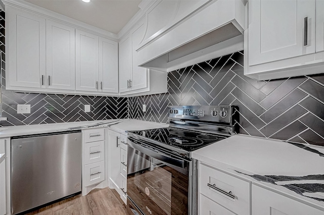 kitchen with decorative backsplash, white cabinetry, stainless steel electric range oven, and fridge