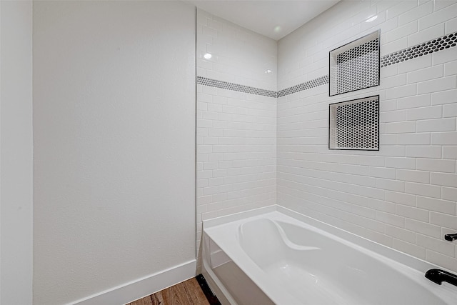 bathroom with hardwood / wood-style floors and tiled shower / bath