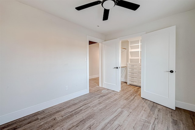 unfurnished bedroom with light wood-type flooring, a closet, a spacious closet, and ceiling fan