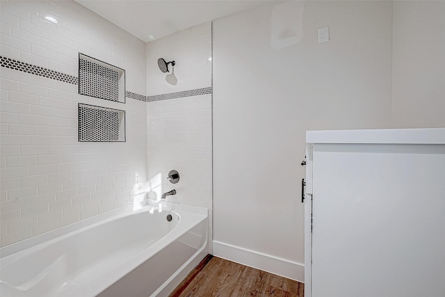 bathroom with hardwood / wood-style flooring and tiled shower / bath combo