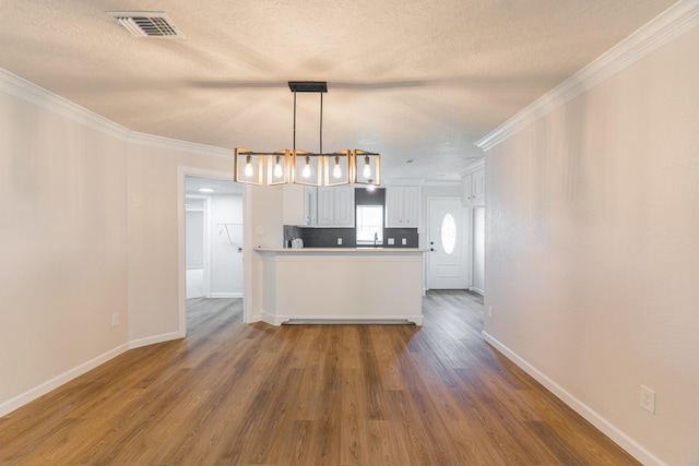 kitchen featuring decorative light fixtures, white cabinetry, hardwood / wood-style flooring, and ornamental molding