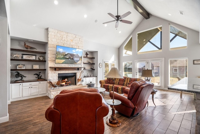 living room featuring built in shelves, ceiling fan, high vaulted ceiling, beamed ceiling, and a fireplace