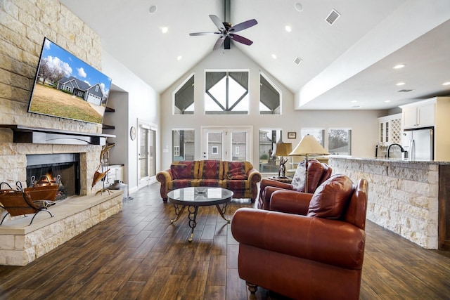 living room featuring ceiling fan, sink, dark hardwood / wood-style flooring, high vaulted ceiling, and a fireplace