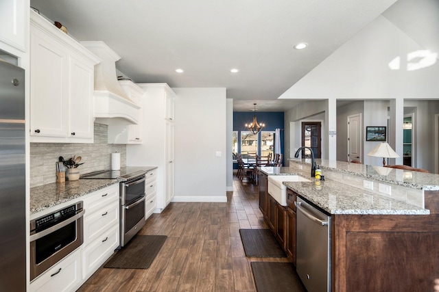 kitchen with a large island with sink, white cabinets, sink, a notable chandelier, and stainless steel appliances