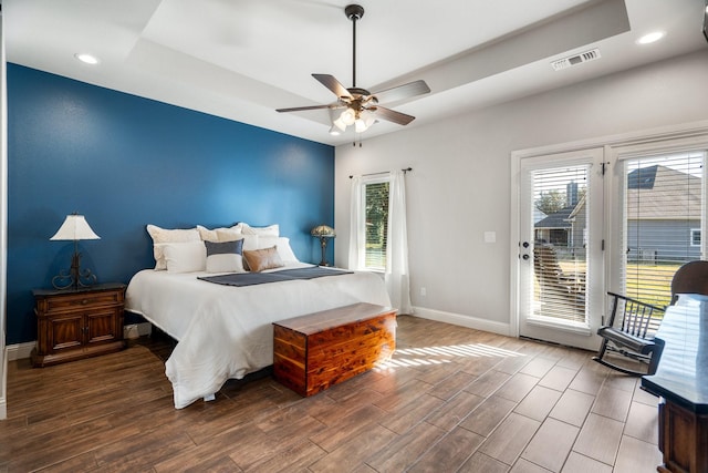 bedroom with ceiling fan, access to outside, and a tray ceiling