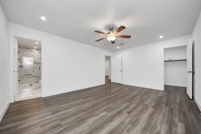 unfurnished bedroom featuring ensuite bathroom, dark hardwood / wood-style flooring, a walk in closet, ceiling fan, and a closet