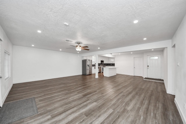 unfurnished living room featuring ceiling fan, dark hardwood / wood-style flooring, and a textured ceiling