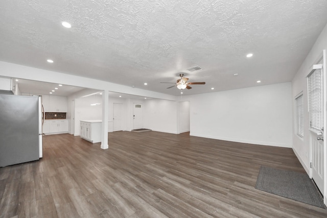 unfurnished living room featuring ceiling fan, dark hardwood / wood-style flooring, and a textured ceiling