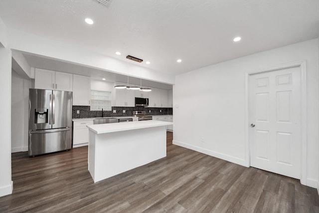 kitchen with white cabinetry, decorative light fixtures, a center island, stainless steel appliances, and backsplash