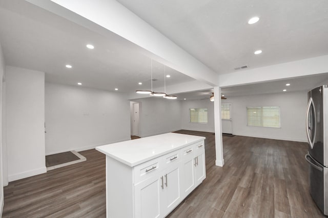 kitchen featuring white cabinetry, stainless steel fridge, hanging light fixtures, a center island, and dark wood-type flooring