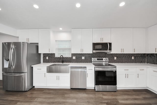 kitchen with appliances with stainless steel finishes, sink, backsplash, white cabinets, and dark hardwood / wood-style flooring