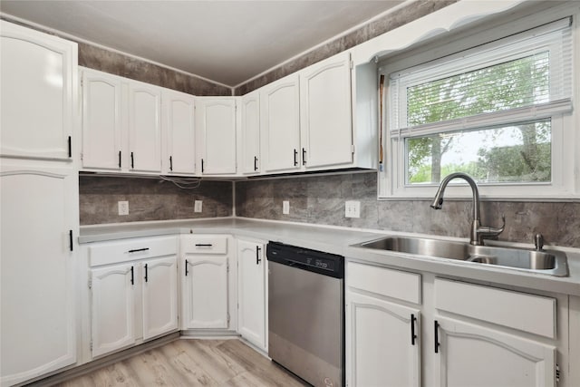 kitchen featuring white cabinetry, sink, stainless steel dishwasher, light hardwood / wood-style floors, and decorative backsplash