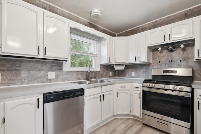 kitchen featuring white cabinetry, sink, stainless steel appliances, backsplash, and light hardwood / wood-style floors