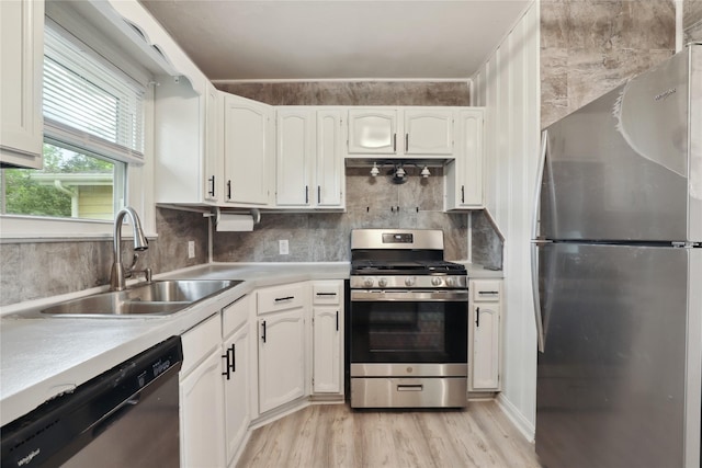 kitchen featuring white cabinetry, sink, stainless steel appliances, decorative backsplash, and light wood-type flooring