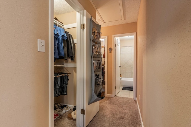 hallway featuring light colored carpet and a textured ceiling