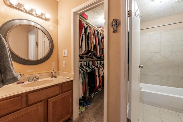 bathroom featuring tile patterned flooring, vanity, tiled shower / bath combo, and a textured ceiling