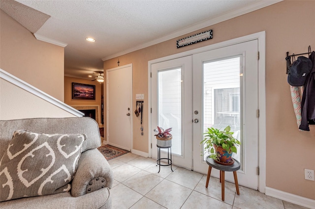 tiled foyer entrance featuring ceiling fan, french doors, a textured ceiling, and ornamental molding