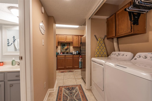 laundry area with washer and clothes dryer, cabinets, light tile patterned floors, and sink