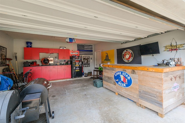 garage featuring a workshop area, black refrigerator, and a garage door opener