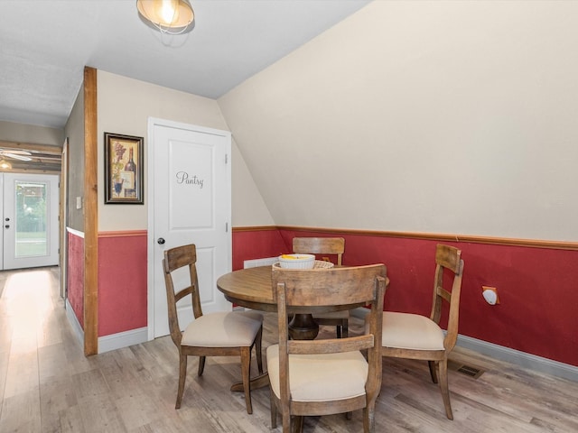 dining room featuring light wood-type flooring and vaulted ceiling