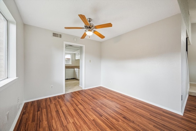 empty room featuring a healthy amount of sunlight, ceiling fan, and light hardwood / wood-style floors