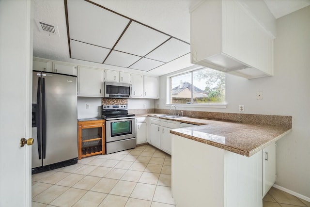 kitchen with sink, white cabinets, light tile patterned floors, and appliances with stainless steel finishes