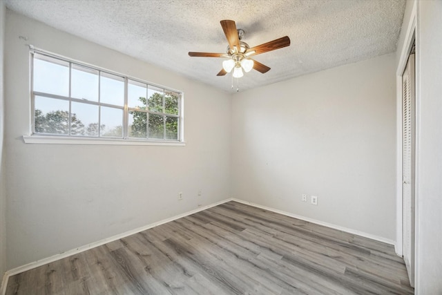 unfurnished bedroom with ceiling fan, a closet, light hardwood / wood-style floors, and a textured ceiling