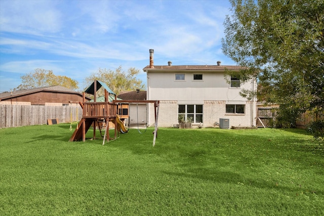 rear view of property with a lawn, a playground, and central AC unit