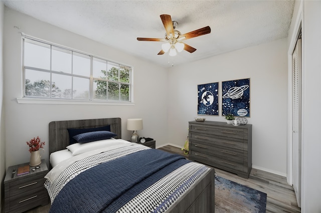 bedroom with hardwood / wood-style floors, ceiling fan, a textured ceiling, and a closet