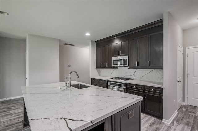 kitchen with tasteful backsplash, sink, a kitchen island with sink, and stainless steel appliances