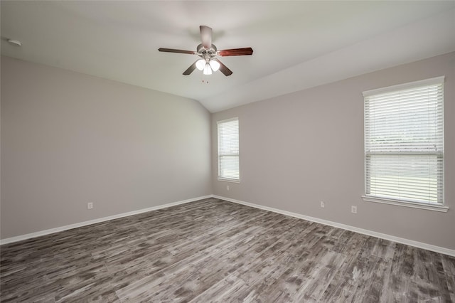 empty room with ceiling fan, dark hardwood / wood-style floors, and vaulted ceiling