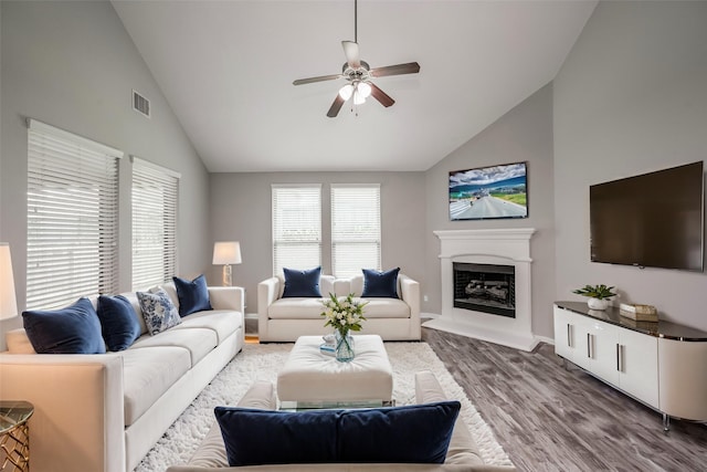 living room with ceiling fan, wood-type flooring, and vaulted ceiling