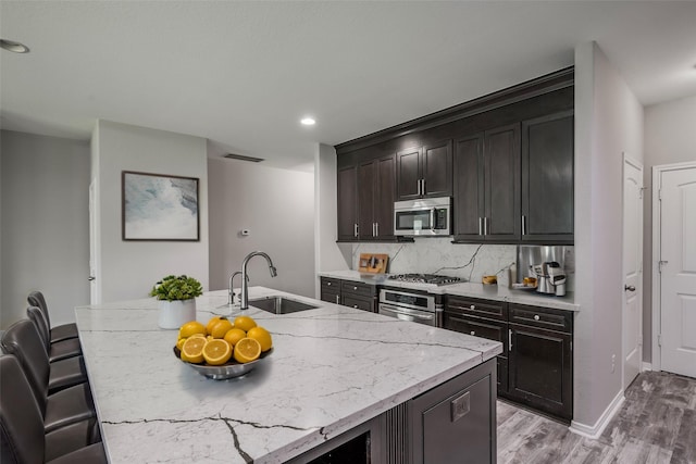 kitchen with stainless steel appliances, tasteful backsplash, a center island with sink, and sink