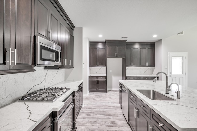 kitchen featuring light stone countertops, sink, stainless steel appliances, and light hardwood / wood-style floors