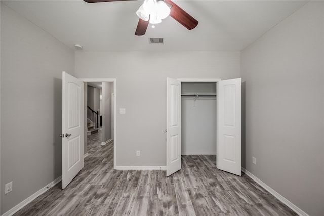 unfurnished bedroom featuring hardwood / wood-style flooring, ceiling fan, and a closet