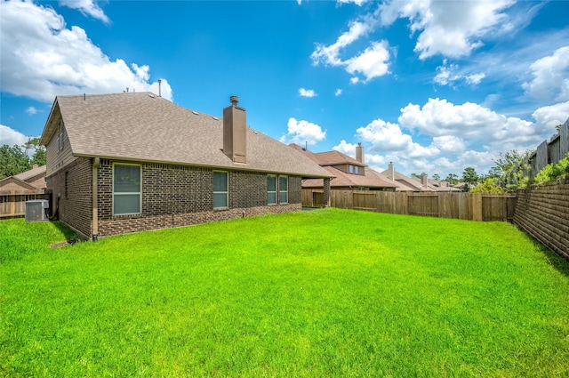 rear view of property with a yard and central air condition unit