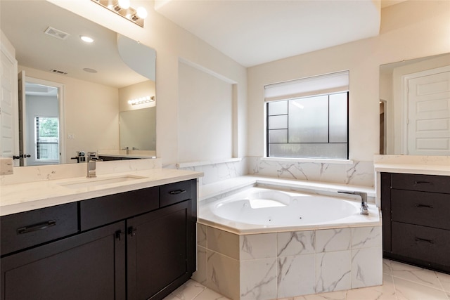 bathroom with vanity and tiled tub