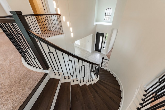 staircase featuring a towering ceiling and hardwood / wood-style flooring