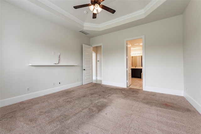 unfurnished bedroom with light carpet, ensuite bath, ornamental molding, a tray ceiling, and ceiling fan