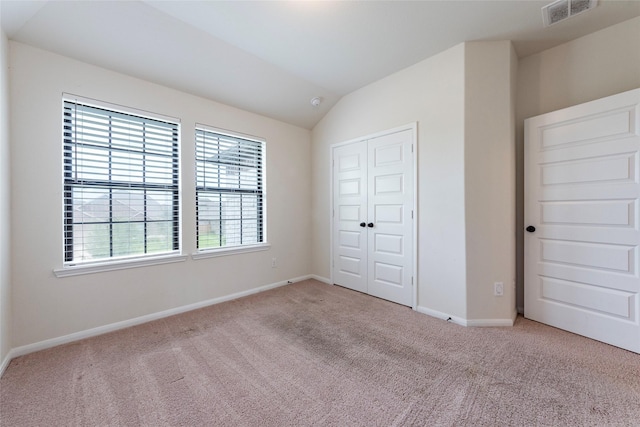 unfurnished bedroom featuring light carpet, a closet, and vaulted ceiling