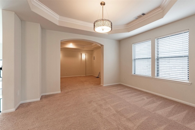 carpeted empty room with a raised ceiling and crown molding